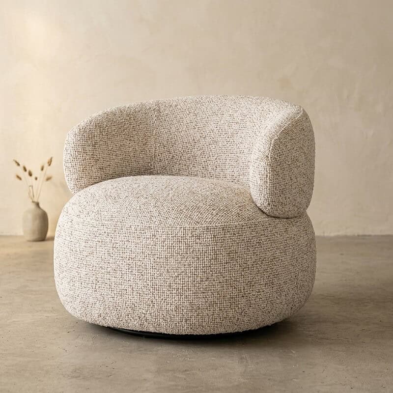 Moderne stoffen fauteuil met ronde vormen, comfortabele zitting en zachte bekleding, perfect voor een stijlvolle en gezellige woonkamer.