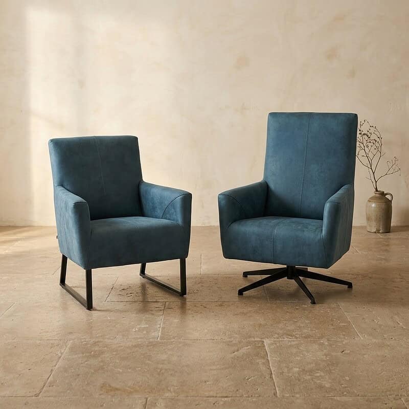 Twee moderne fauteuils, een met houten poten en een met draaibare onderstel, in een minimalistische woonkamer met beige muren en houten vloer.
