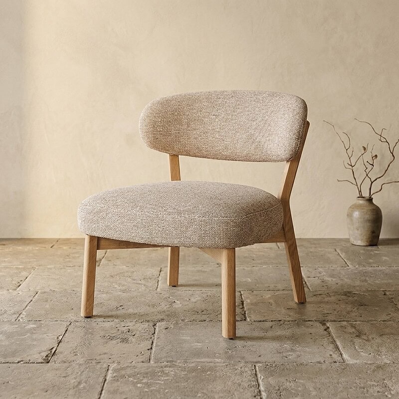 Moderne houten fauteuil met zachte beige bekleding, perfect voor een stijlvolle en comfortabele zithoek in huis.