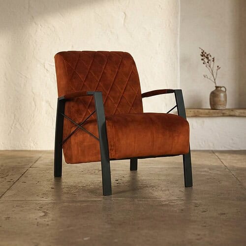 Luxe Mokana fauteuil met oranje fluwelen bekleding en zwart metalen frame, perfect voor moderne woonruimtes en stijlvolle interieurs.