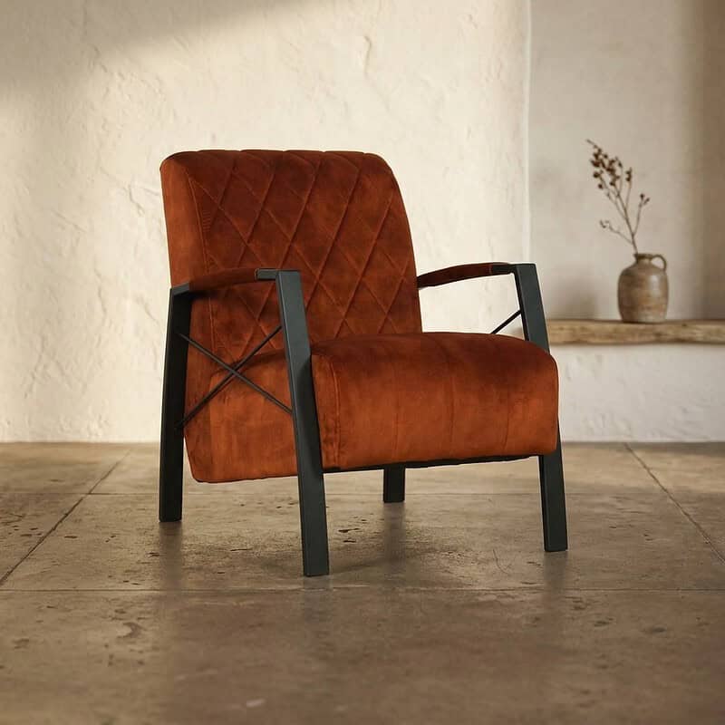 Luxe Mokana fauteuil met oranje fluwelen bekleding en zwart metalen frame, perfect voor moderne woonruimtes en stijlvolle interieurs.