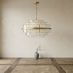 Ein luxuriöser Kronleuchter von Mokana über einem minimalistischen Raum mit einer Vase und einem Zweig – perfekt für moderne Inneneinrichtung.