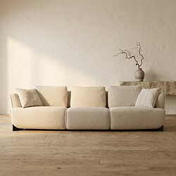 Moderne beige stoffen bank met kussens in een minimalistisch interieur, perfect voor woonkamerdecoratie en comfort.