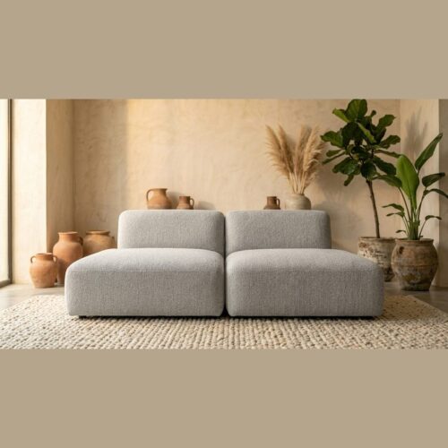 Moderne grijze bank in een minimalistische woonkamer met natuurlijke decoratie en aardetinten, perfect voor een stijlvolle en comfortabele zithoek.
