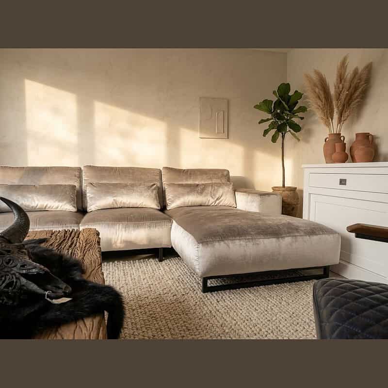 Elegante velvet hoekbank in een stijlvolle woonkamer met natuurlijke lichtinval, perfect voor comfortabel loungen en moderne interieurdecoratie.