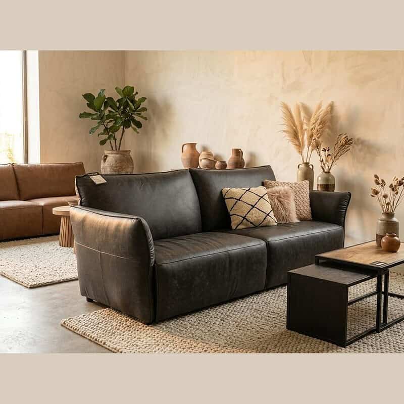 Luxe zwarte leren bank in een moderne woonkamer met natuurlijke decoratie en zachte texturen, perfect voor een elegante en comfortabele zithoek.