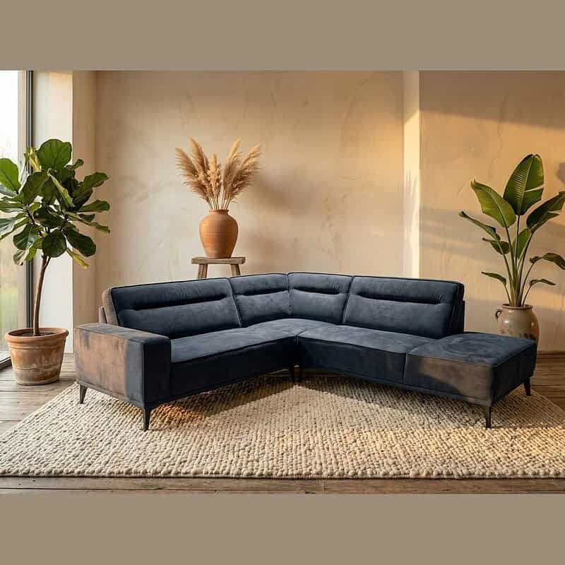 Moderne zwarte stoffen hoekbank in een stijlvolle woonkamer met planten en natuurlijke lichtinval, perfect voor een eigentijdse woonruimte.
