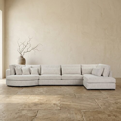 Moderne lichte loungebank in een strakke woonkamer met een decoratieve vaas en takken op de achtergrond, perfect voor een eigentijdse interieurstijl.