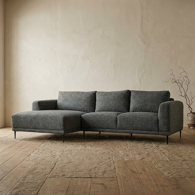 Moderne grijze loungebank in een minimalistische woonkamer met houten vloer en een eenvoudige decoratie, perfect voor een stijlvolle en comfortabele zithoek.