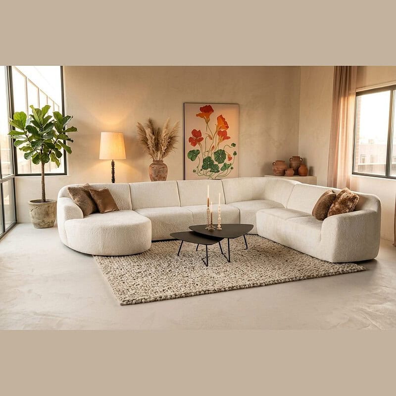 Moderne witte hoekbank in een stijlvolle woonkamer met natuurlijke lichtinval, comfortabele kussens en elegante decoratie, perfect voor een eigentijdse interieurstijl.