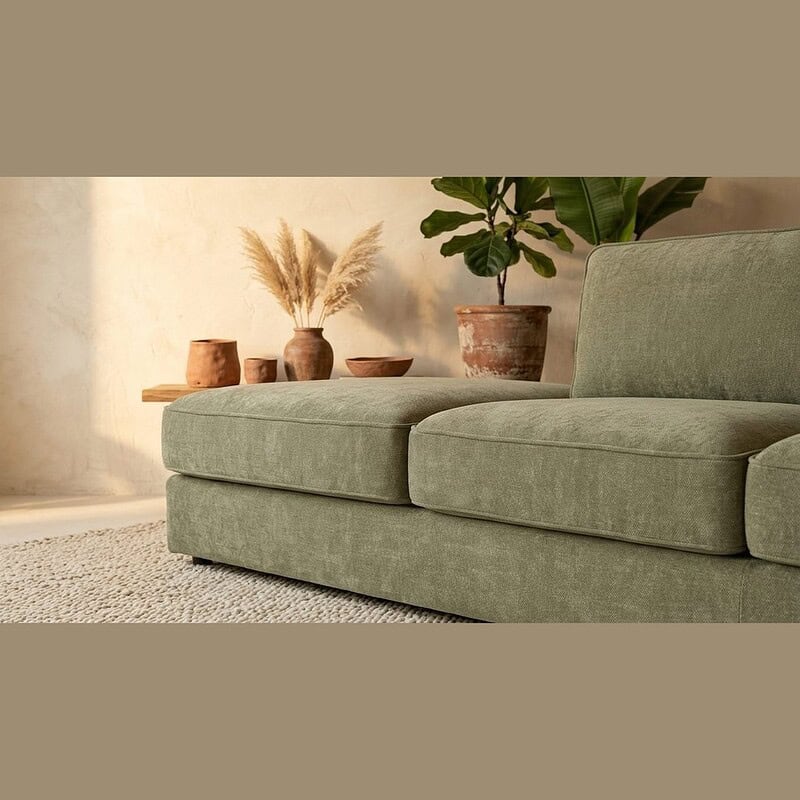 Elegante groene loungebank in een stijlvolle woonkamer met natuurlijke decoratie en planten, perfect voor een moderne en gezellige zithoek.