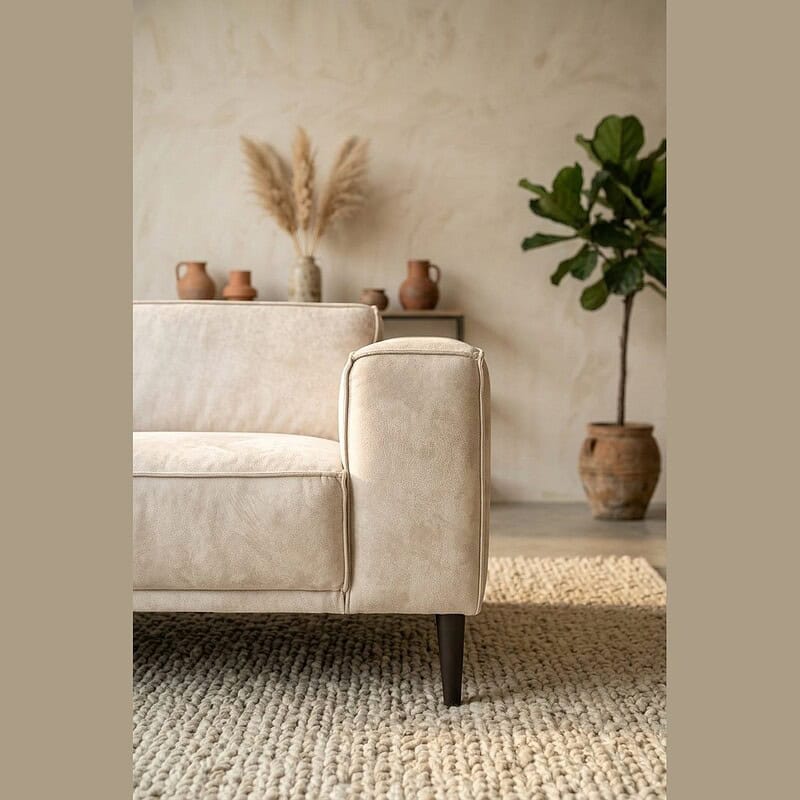Luxe beige bank met houten poten en decoratieve planten Luxe beige bank met houten poten in een stijlvolle woonkamer, gecombineerd met decoratieve planten en aardetinten voor een warme, moderne uitstraling.