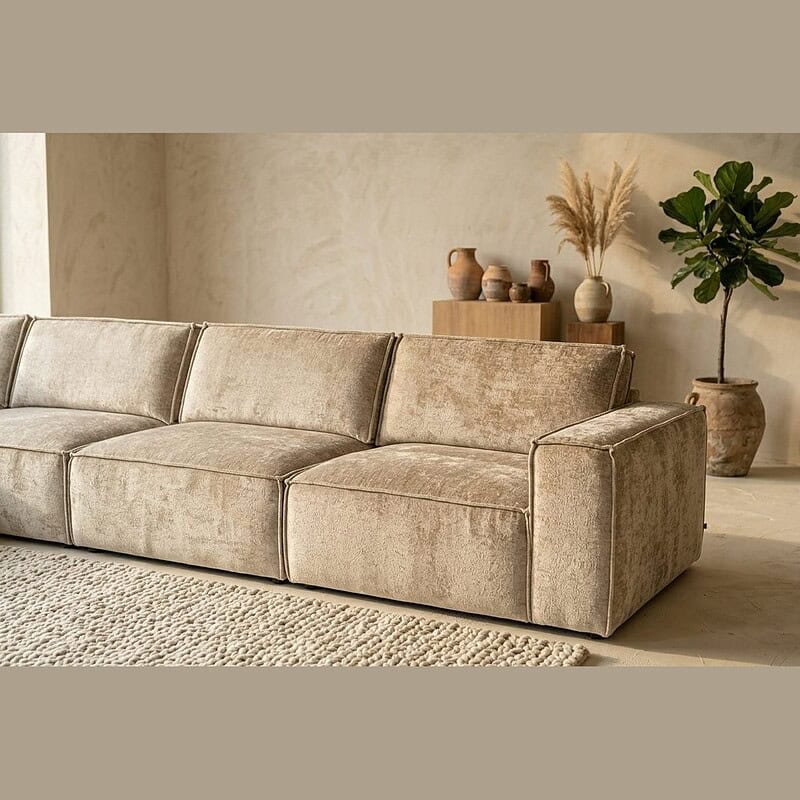 Elegante stoffen bank in een minimalistisch woonkamer met natuurlijke decoratie en planten, perfect voor een stijlvolle en comfortabele zithoek.