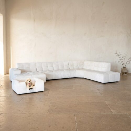Bank met witte bekleding, modern design, geschikt voor gezellige zithoek, in een lichte, minimalistische woonkamer.
