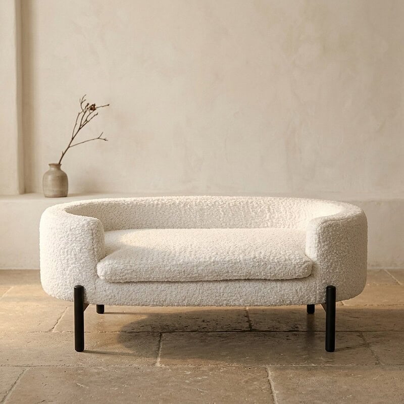 Moderne witte stoffen bank met ronde armleuningen en zwarte poten, perfect voor een stijlvolle woonkamer.