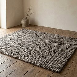 Natuurlijke wollen vloerkleed op houten vloer, minimalistisch interieur, rustieke uitstraling, zachte textuur, duurzame woonaccessoire, handgemaakt tapijt, modern landelijk design, woonkamer decoratie.