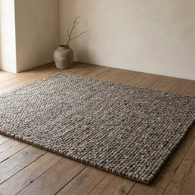 Natuurlijke wollen vloerkleed op houten vloer, minimalistisch interieur, rustieke uitstraling, zachte textuur, duurzame woonaccessoire, handgemaakt tapijt, modern landelijk design, woonkamer decoratie.