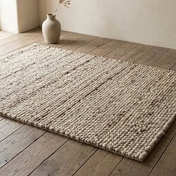 Neutraal wollen vloerkleed met textuur en zachte kleuren, ideaal voor een moderne woonkamer of slaapkamer.