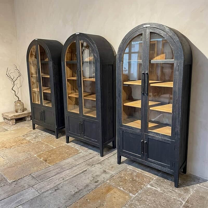 Kast met glazen deuren en houten planken Drei schwarze Vitrinen aus Holz mit Glastüren und Einlegeböden, ideal zur Präsentation von Dekoartikeln oder Geschirr in einer stilvollen und modernen Einrichtung.