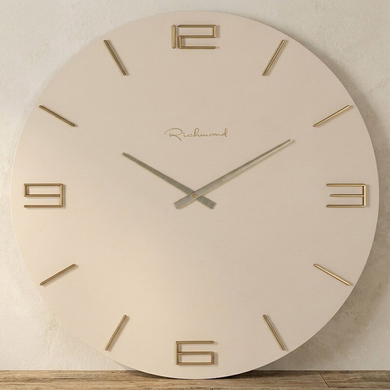 Moderne wandklok met een minimalistisch ontwerp, witte achtergrond en gouden cijfers, geschikt voor woon- en kantoorinterieurs.