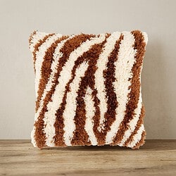Zacht, pluizig kussen met zebra-strepen in bruin en wit, perfect voor een gezellige woonkamer of slaapkamer.