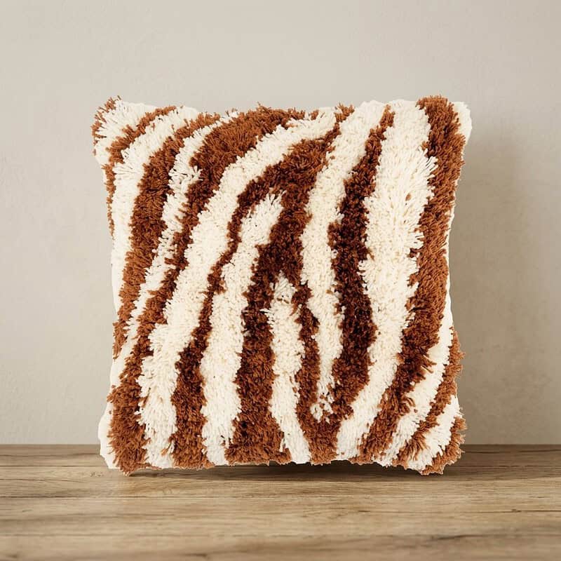 Zacht, pluizig kussen met zebra-strepen in bruin en wit, perfect voor een gezellige woonkamer of slaapkamer.