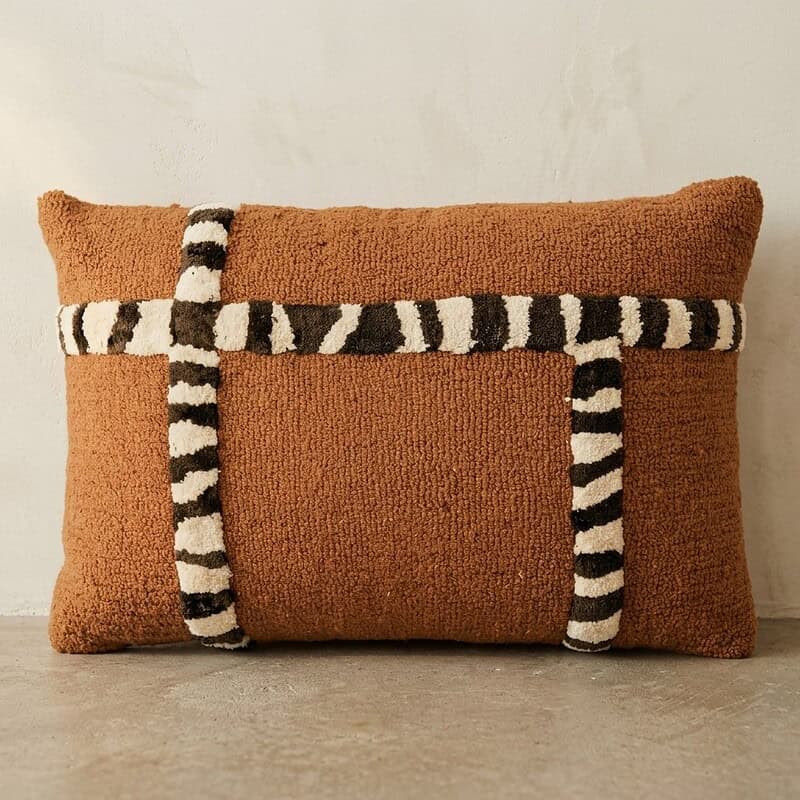 Decoratief kussen met een rustieke textuur en opvallende zwart-wit gestreepte banden, perfect voor een gezellige en stijlvolle woonkamer.