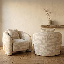 Comfortabele beige stoffen fauteuil en bijzettafel met vaas in een strakke, minimalistische woonkamer, perfect voor een stijlvolle en gezellige zithoek.