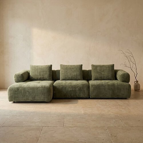Bank met groene bekleding en kussens, minimalistisch interieur.