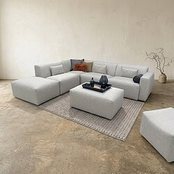 Moderne Lounge-Ecke mit Möbeln von Mokana, bequemer Eckcouch und passendem Hocker, im minimalistischen Einrichtungsstil.