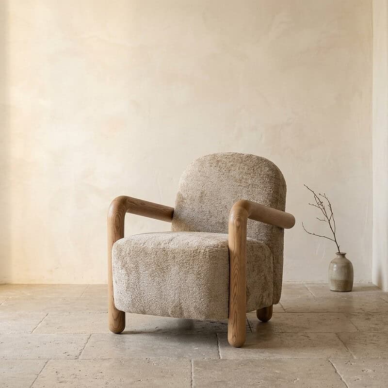 Bequemer Sessel aus Holz und Stoff in einem minimalistischen Interieur mit natürlichen Farben und schlichter Dekoration.