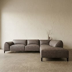 Moderne grijze leren bank met chaise longue in minimalistisch interieur, geschikt voor stijlvolle woonkamers.