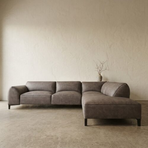 Moderne grijze leren bank met chaise longue in minimalistisch interieur, geschikt voor stijlvolle woonkamers.