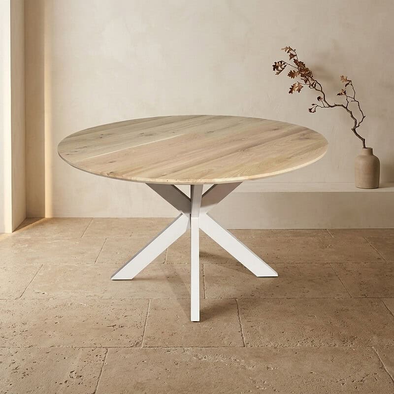 Moderne ronde eettafel met houten blad en witte metalen onderstel, perfect voor een eigentijdse eetkamer of woonkamer.