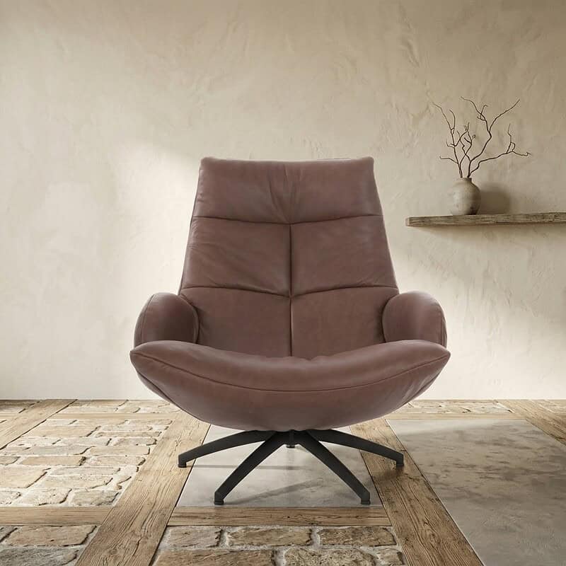 Zachte roze leren lounge fauteuil met comfortabele zitting en rugleuning, op een zwarte draaivoet, geplaatst in een minimalistische interieursetting.