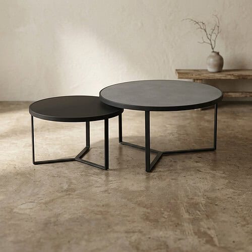 Twee strakke, moderne bijzettafels met zwarte metalen frames en ronde, donkergrijze bladen, perfect voor een eigentijdse woonkamer of lounge.