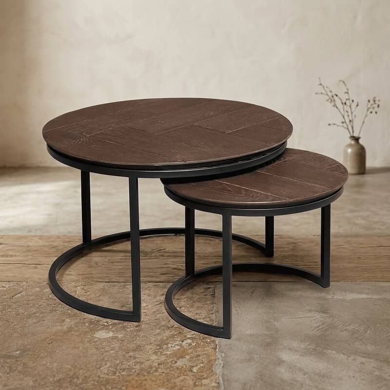 Moderne set van twee ronde bijzettafels met donkerhouten bladen en zwart metalen onderstellen, ideaal voor woonkamer of lounge.