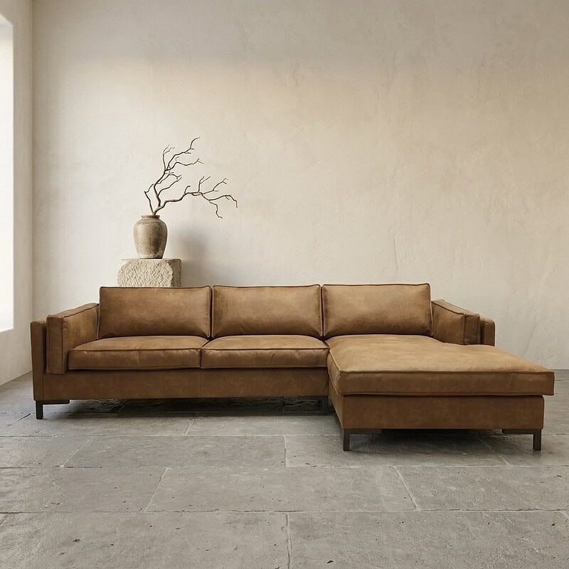 Luxe leren hoekbank in bruin met chaise longue, perfect voor moderne woonkamers, gecombineerd met minimalistische decoratie en natuurlijke elementen.