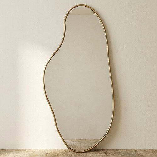 Grote gouden spiegel met golvend frame in minimalistisch interieur Grote gouden spiegel met golvend frame, ideaal voor modern interieur, decoratief en functioneel, grote spiegel voor woonkamer of slaapkamer.