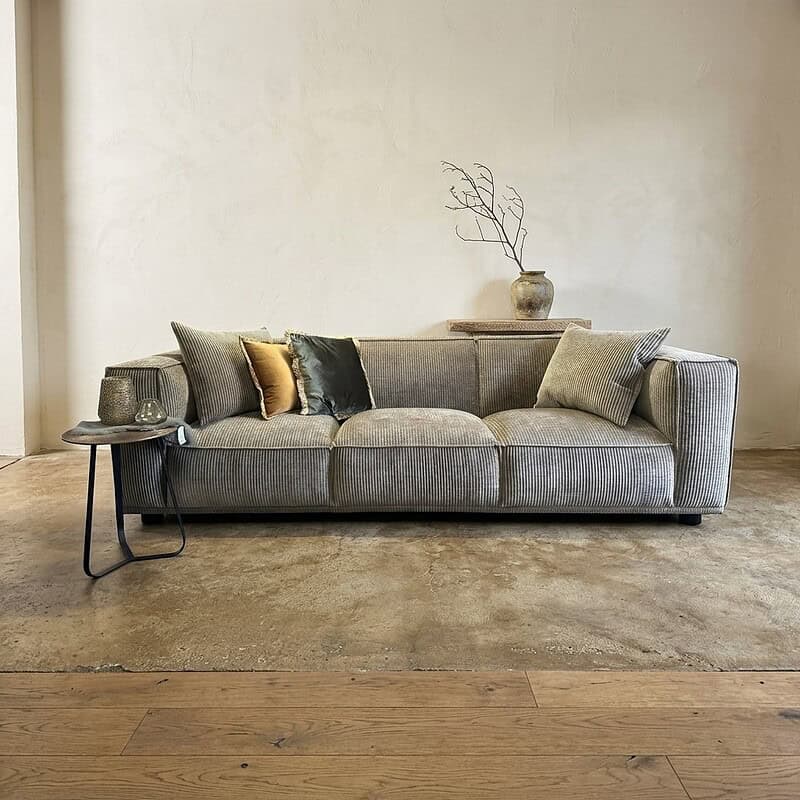 Moderne stoffen bank met decoratieve kussens in een strakke woonkamer, perfect voor een stijlvolle en comfortabele zithoek.