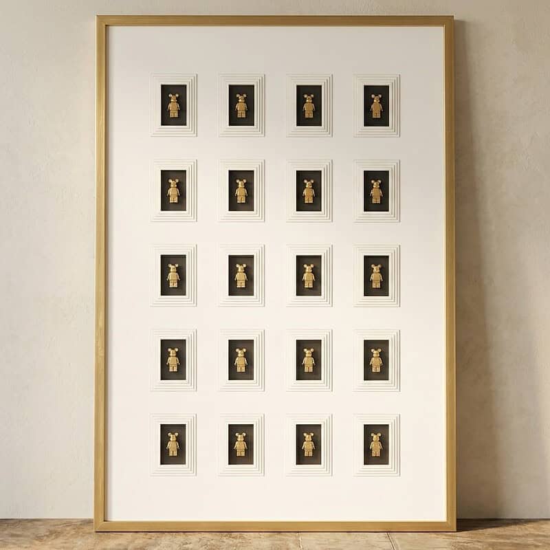 Kunstwerk met 20 gouden poppetjes in zwart en wit lijst, perfect voor moderne interieurdecoratie, ontworpen door Mokana Meubelen.