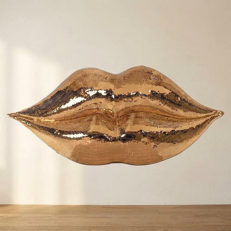Gouden lipvormige spiegel als decoratief kunstwerk, perfect voor moderne interieuraccenten en stijlvolle woonruimtes.