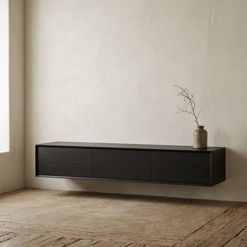 Moderne wandmeubel in zwart hout met drie lades, geplaatst in een lichte kamer met natuurlijke lichtinval, perfect voor een eigentijdse woonstijl.