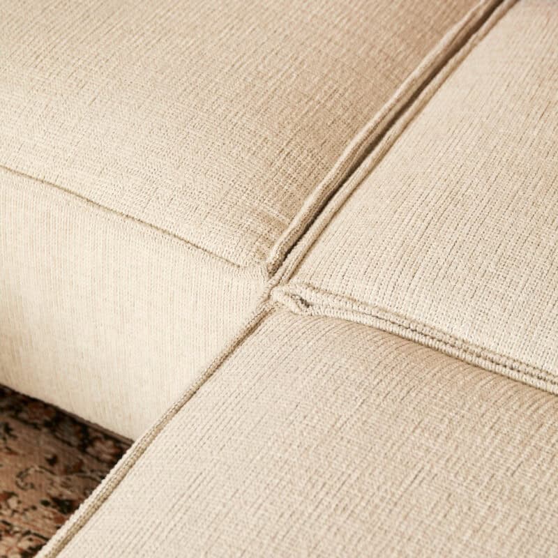 Close-up van een beige stoffen bank van Mokana Meubelen, met aandacht voor de textuur en afwerking.