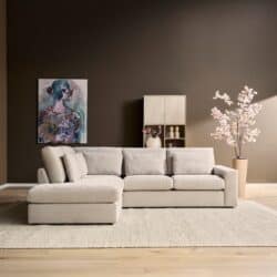 Luxe woonkamer met moderne Mokana meubelen, beige bank, kunstwerk en bloemen in een stijlvolle interieur setting.