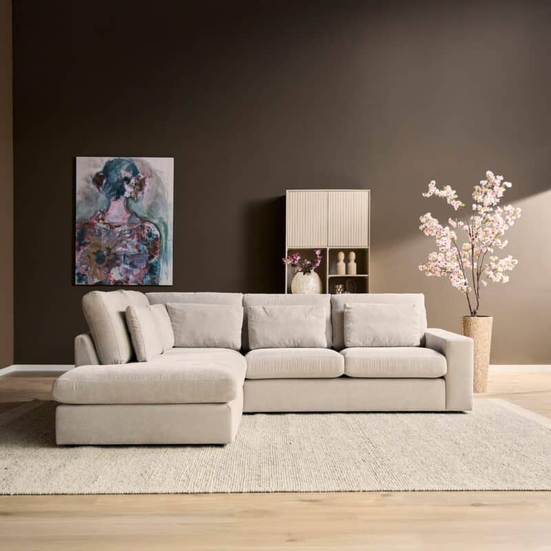 Luxe woonkamer met moderne Mokana meubelen, beige bank, kunstwerk en bloemen in een stijlvolle interieur setting.
