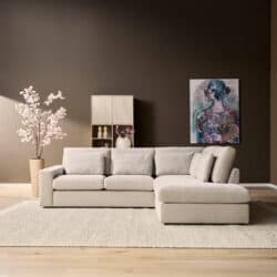 Luxe beige hoekbank in moderne woonkamer met kunstwerk en bloemen, perfect voor stijlvolle interieurs.