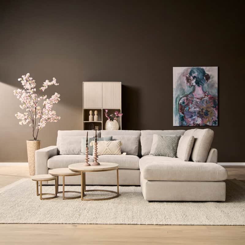 Moderne woonkamer met lichte bank, bijzettafels, kunstwerk en decoratieve planten, perfect voor stijlvolle woonruimtes.