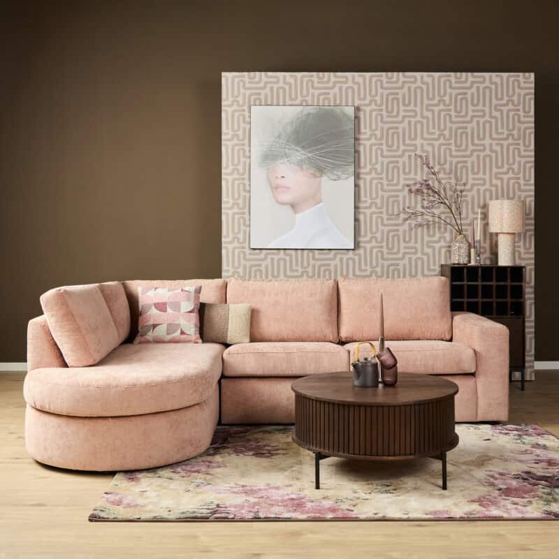 Luxe roze bank van Mokana Meubelen in een modern interieur met decoratieve accessoires en kunstwerk op de achtergrond.