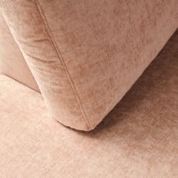 Close-up van een meubelstuk met zachte, lichtroze bekleding en een comfortabele uitstraling, perfect voor moderne woonkamers.